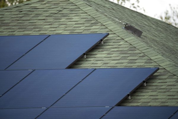 Ordinary residential house in USA with roof covered with solar panels for producing of clean ecological electricity in suburban rural area. Concept of investing in autonomous home for energy saving.